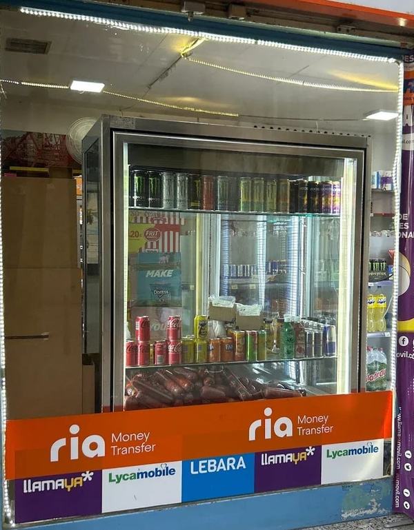 La nevera de begudes de Tienda Ouassim vista des de l'aparador, amb llaunes de refrescos i begudes energètiques
